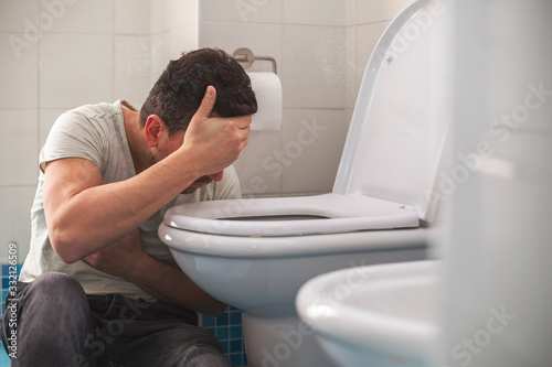 Man feeling bad putting his head in toillet and vomiting.