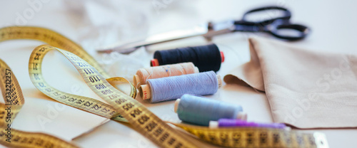 Composition of seamstress threads and scissors on a white table. Concept of a clothing designer