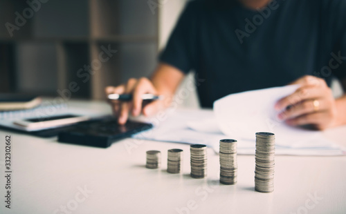 Asian men are calculating about finances about the cost or future investment at home while the coins are arranged with the idea of saving.