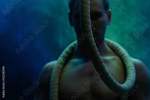 Muscular male circus artist with Cord Lisse on black an smoked background