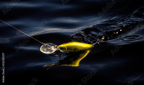 Fishing hook with lure and fishing wire. Dark blue water. 