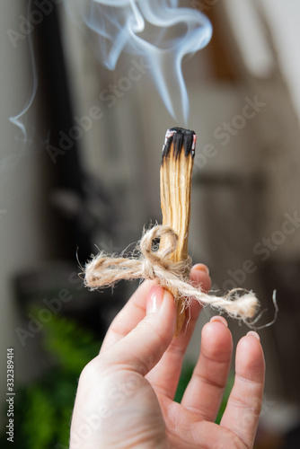 Naturalna aromaterapia w domu. Kobieca ręka trzyma dymiące się drewienko, kadzidło. 