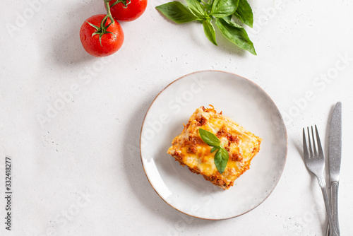 Piece of tasty hot lasagna served with a basil leaf on a gray plate. Italian cuisine, menu, recipe. Homemade meat lasagna. Copy space, top view