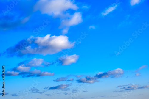 White clouds in clear spring weather, copy space. Sunny sky in the morning with floating clouds. Background of cloudy blue sky.