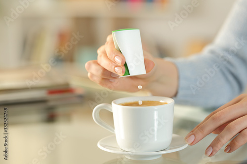 Woman hand throwing saccharin pills on coffee cup