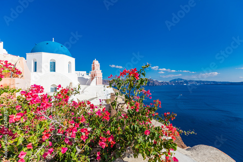 Wonderful scenery, summer travel landscape, vacation background. Flowers on the terrace. Beautiful landscape with sea view. White architecture on Santorini island, Greece.