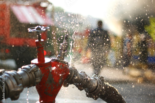 Water splashes from the fire hose and hydrant connections. Firefighters Work Concept