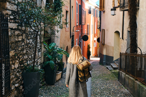A beautiful woman with blond hair walks through the streets of the city. Girl enjoy holidays in Europe. Beautiful historical architecture. Switzerland weekend. Travel to Locarno, Swiss. Adventure life