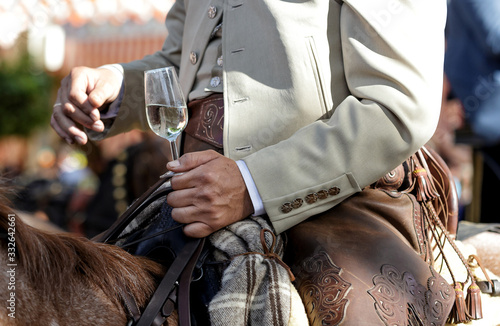 Rider on horseback dressed in traditional costume and holding glass of fino sherry (manzanilla sherry) at the April Fair (Feria de Abril) Andalusia, Spain. Travel and tourism concepts