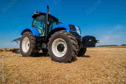New blue tractor working on the field, modern agricultural vehicle