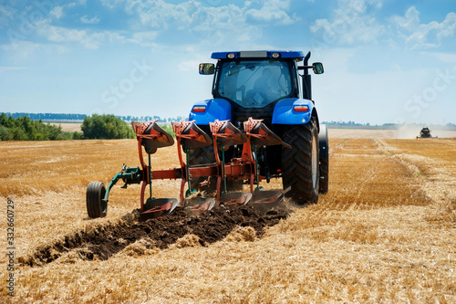 A plow attached to a blue tractor, arable land, field preparation
