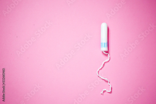 Medical female tampon on a pink background with copy space. Hygienic white tampon for women. Cotton swab. Menstruation, means of protection.