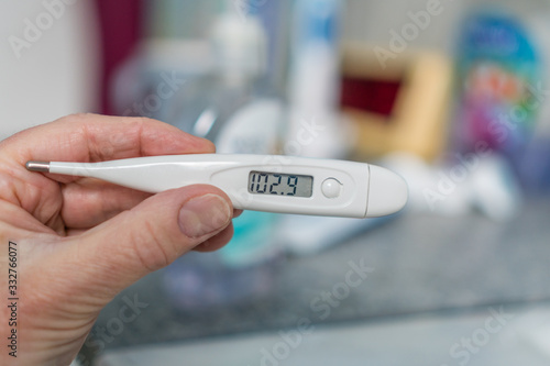 Close-up of hand holding thermometer measuring a high fever.