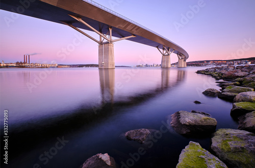 Big bridge going over a cove with stones foreground and a city in the background