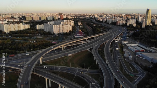 Aerial drone view of highway multi-level junction road with moving cars at sunset. Cars are moving on a multi-level road junction