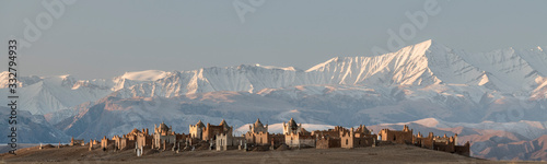 first morning sunlight falling on the cemetery of Terek, south of Baetov, near the Mels-Ashu pass with the amazing landscape of the Tian Shan mountains covered in snow around