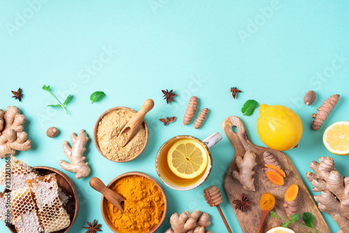 Spicy healthy turmeric drink with lemon, ginger, honey on blue background. Immune system booster food, antiviral beverage. Vegan hot drink concept.