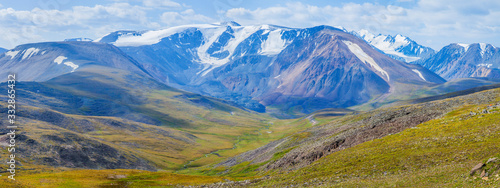 Panoramic view of a mountain valley. Tundra, treeless mountain slopes, snow-capped peaks. 
