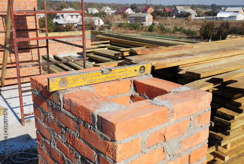Building a chimney out of masonry, noncombustible red bricks and cement on the rooftop of a house.