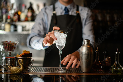 bartender holds transparent glass covered by sieve