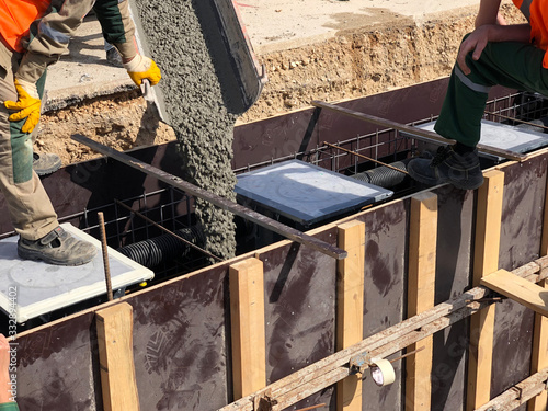 Construction workers are pooring concrete to formwork