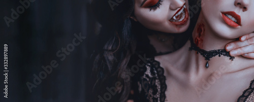 Artwork close up portrait evil medieval vampire woman bites tender cute girl princess. Drop blood red sexy lips. Bloody scary wound bite on neck. Woman's Vampire mouth teeth fangs. Horror bloddy kiss