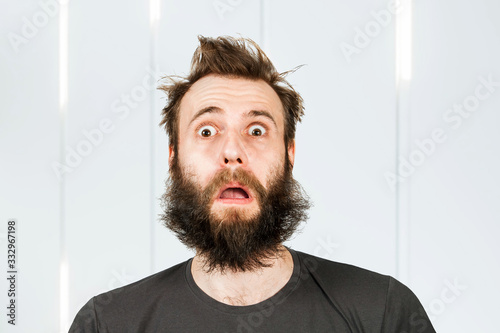 Portrait freak bearded shaggy surprised man with long hair before haircut in barbershop with open mouth and wide eyes