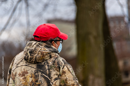 Man in a red cap wearing a face mask whle riding a bike in the park