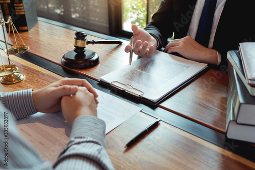 Lawyer working with client discussing contract papers with brass scale about legal legislation in courtroom, consulting to help their customer.