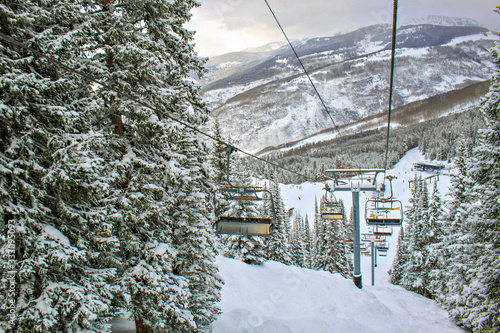 Empty ski lift in Vail Colorado next to giant snow-covered tree