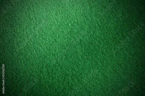 Poker table felt background in dark green color with shade vignette.