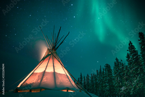 Glowing tipi / teepee in the snowy forest under the northern lights, Yellowknife, Northwest Territories, Canada