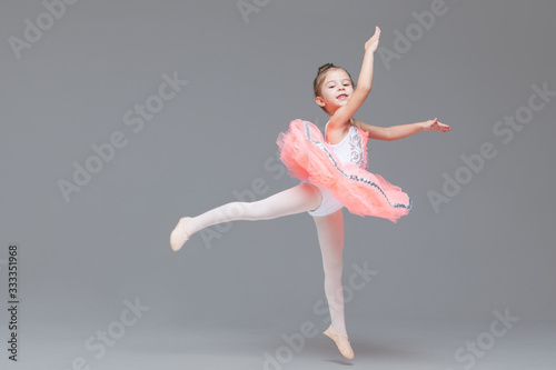 Cute adorable ballerina little girl in pink tutu dance practices ballet dancing