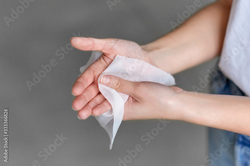 hygiene, health care and disinfection concept - close up of woman cleaning hands with antiseptic wet wipe