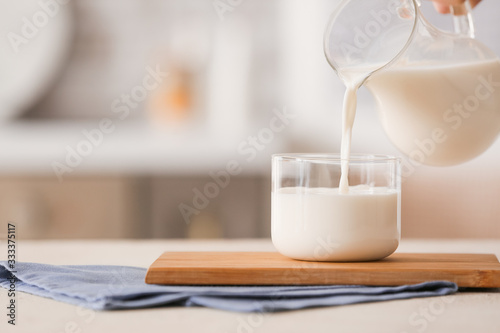 Pouring of milk into glass on table