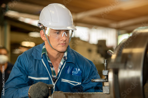 Technician working on lathe spare part machine in iron manufacturing factory,Works in a lathe concept.