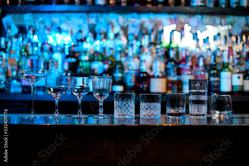 Several glasses of different forms stand on bar counter.