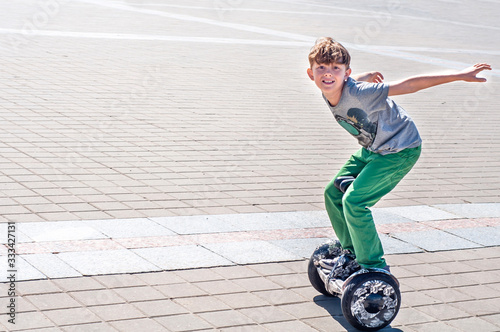 Fashionable teen boy rides a giroskuter in the city square. Fashion for gyro scooters and gyroboards among teenagers. Active children's leisure in the summer. Smart eco transport segway