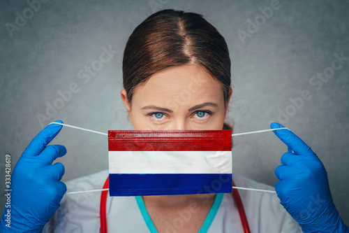 Coronavirus in Netherlands Female Doctor Portrait hold protect Face surgical medical mask with Netherlands National Flag. Illness, Virus Covid-19 in Netherlands, concept photo