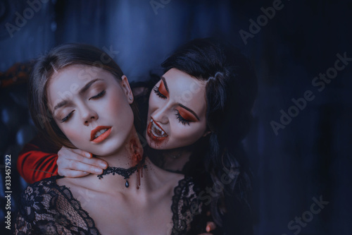 Close Up artwork portrait face sexy vampire woman bites eating drinks young princess. Makeup Drop blood. Bloody wounds bite on neck blonde girl. Horror night halloween. Holiday scary make-up red lips 