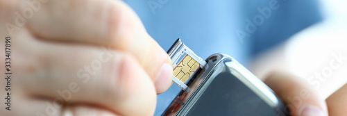 Male hands getting sim card slot of his smartphone out