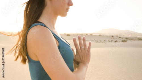 Closeup of young woman meditating in desert. Hands of woman with silver wave ring while practicing yoga.