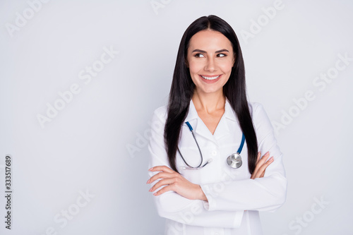 Photo of attractive practitioner lady toothy smile consultation rehabilitation center arms crossed look interested empty space wear lab coat stethoscope isolated grey color background