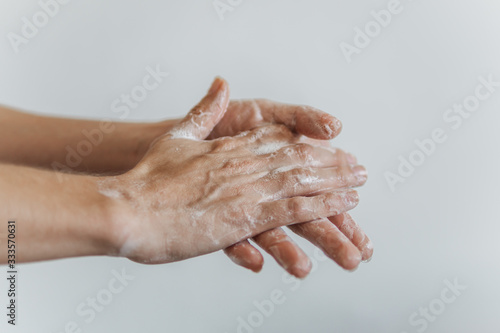 Detalhe de mãos femininas com espuma de sabonete. Lavar as mãos para combater o coronavírus.