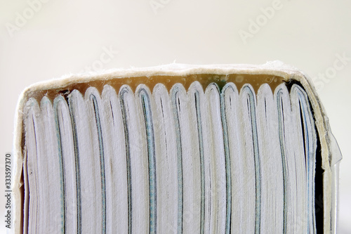 A book bound using perfect binding showing the spine and glue holding folded sections of the book together. Pages of a book glued together with the cover using a strong adhesive. Closeup macro view.