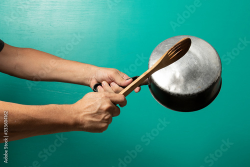 person hitting pot to protest, with a green background.