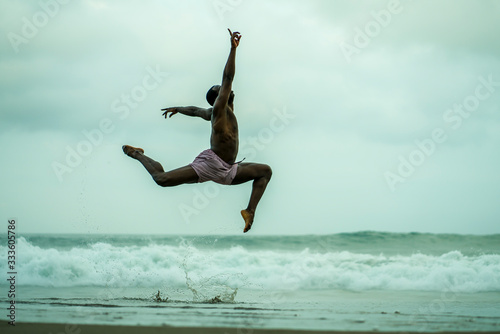 dance choreographer and dancer doing ballet beach workout - young attractive and athletic black African American man dancing outdoors doing beautiful performance