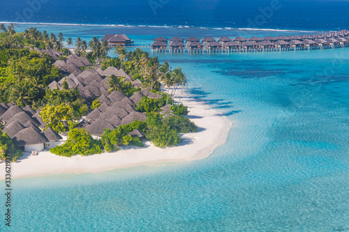 Luxury water villas and bungalows in Maldives sea, palm tree, beautiful summer weather. Aerial photo of beautiful paradise Maldives tropical sunny beach on island. Summer and travel vacation concept.