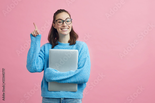 Smart looking student on colorful background holding her finger up to signal that she have an good idea 