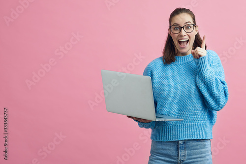 Excided student holding a computer and holding her finger up to show that she got a good idea